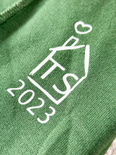 Laden Sie das Bild in den Galerie-Viewer, Dunkelgrüner Pullover Detailansicht vorne. Ein kleines Haus mit den Anfangsbuchstaben des Paares und das Jahr darunter