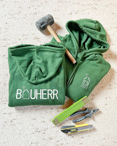 Dunkelgrüner Kapuzenpullover mit der Aufschrift Bauherr auf dem Rücken. 